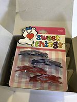 One pack of four plastic hair clips, two blue and two brown clips, brand 'sweet things' with bear logo on packaging