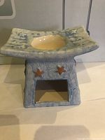 Front angle of ceramic incense burner showing the square top dish with a yellow bowl and star-shaped cutouts on the base.