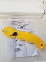 Plastic yellow package opener laid on an instruction sheet describing usage.