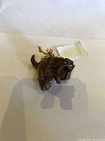 Front angled view of brown hound dog ornament with gold hanging string, showing facial details and sitting pose.