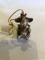 Front view of baby dragon figurine tree ornament with big eyes and gold hanging string attached to top.
