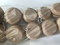 Close-up of 10 wooden yo-yos packed together inside clear plastic packaging, showing natural wood grain and attached strings.