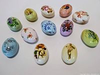 Top view of all 12 hand painted porcelain eggs in varied floral patterns and colors including poinsettias.