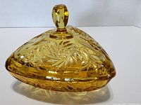 Amber glass covered candy dish with triangular shape and knob lid handle showing pinwheel pattern