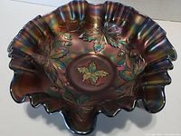 Top view showing the detailed embossed acorn and leaf pattern, iridescent color shifting in bronze, green and purple hues, and ruffled rim shape.
