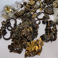 Close-up image of several ornate brass drawer pulls and handles with intricate designs.