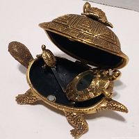 Opened brass turtle trinket box showing interior and smaller turtles inside