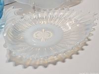 Close-up of white opalescent Fostoria Heirloom bon bon dish showing sunburst pattern and ruffled edges.
