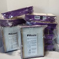 12 sealed Filtrete Type B air filters stacked in packaging showing white pleated filter surface and cardboard frame.