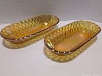 Two amber carnival glass dishes with pretzel pattern shown from the top and side angles