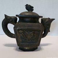Front view of the square Yixing teapot with dragon handle and spout, showing dragon detail on the side panel.