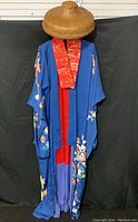 Full view of the blue Japanese silk kimono with red inner lining and floral patterns, displayed with the conical reed hat on top.