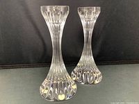 Front view of two Baccarat crystal candle sticks showing flared base and vertical cuts.