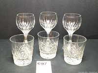 Front view of three Massena red wine glasses and three whiskey tumblers arranged in two rows on black background