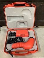 Open orange carrying case showing handheld emitter, power unit, coiled cable