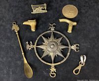 Overview of the 7 brass decor items including nautical compass, 2 cane handles, letter holder, shoehorn, seal, and key clip on black backdrop