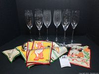Front view of six etched champagne glasses, folded napkins and punch ladle