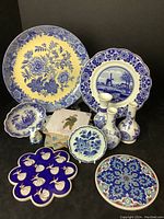 Full group showing large floral plate, windmill plate, smaller plates, vases, tiles, coasters, and papers.
