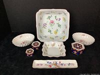 Full lot view showing all floral design china pieces on black background.