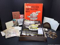 Photo showing the complete collection including the stamp album box, stamps, envelopes, stone piece, geode, and coins.