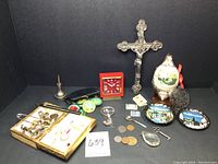 Overview of mixed items from dresser including crucifix, ornaments, clock, coasters, coins, and small accessories