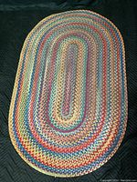 Full view of oval multicolor braided wool rug showing overall shape and color pattern.