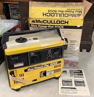 Front angle view of yellow McCulloch Mac Power-Pac 800E generator with original box and manual beside it