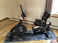 Side profile of black Nautilus R616 recumbent bike on rug showing frame, seat and pedals