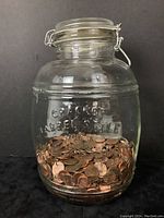 Full view of Cracker Barrel style glass jar containing pennies about 2.75 inches deep.
