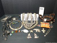 Group shot of necklaces, bracelets, belt, and pins arranged on black background