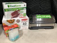 Photo of FoodSaver vacuum sealer with FoodSaver brand vacuum bags and boxes of Rubbermaid TakeAlongs 40-piece set and Hefty compost bags