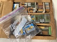 Overhead view of a box containing several small boxes and packages of turntable needles, including a large Ziploc bag with additional needles inside.