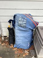 Blue folded bag containing inflatable boat leaning against exterior wall