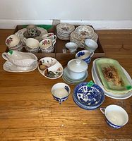 Full view of the mixed dinnerware set on floor showing plates, cups, trays, and gravy boat