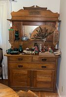 Front view showing entire solid wood hutch with various decorative items on display shelf and drawers/cupboards below.
