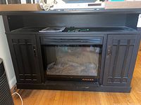 Front view of black engineered wood console with two cupboard doors and central electric firebox insert