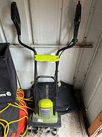 Full view of the Sunjoe TJ600E electric rototiller showing handles, safety bar, and part of the tiller tines.