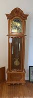 Full view of Daniel Dakota grandfather clock, wood carved details, medium brown finish, approx 17.5x9x72 inches