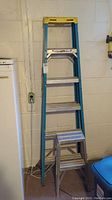 Full view of 6-foot A-frame fiberglass ladder leaning against wall indoors.