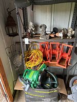 Green Yardworks leaf blower/vac and orange/yellow extension cords and cord reels on metal shelving