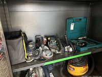 Image showing Ryobi carrying bag, multiple sanding and grinding discs, angle grinder and other power tools on metal shelf.