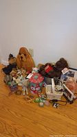 Wide view showing assortment of stuffed animals, winter tin, wooden dog plaque, small puzzle, candles, salt lamp, picture frames, and basket with cords.