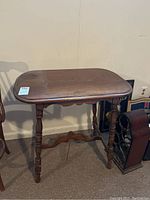 Front view of the stained wooden occasional table with turned legs and rounded rectangular top.