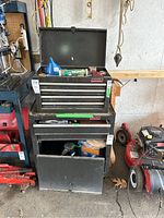 Front view of the black Waterloo tool chest on wheels showing upper drawers open and bottom cabinet door detached, sides with handles, placed in a garage environment.