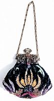 Front view of antique hand beaded evening bag showing colorful floral beadwork and metal clasp with chain handle.