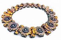 Copper choker necklace laid on white background showing detailed floral metal link design and alternating metal connectors