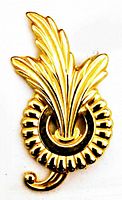 Front view of vintage gold-tone leaf brooch showing detailed leaf blades, circular ridged base, and curled ornamental tip.