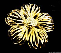 Close-up image of the vintage gold-toned figural flower brooch showing petal details and spiral center.