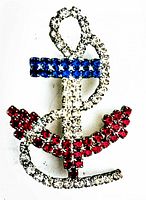 Close-up of vintage rhinestone anchor brooch showing red, blue, and clear rhinestones on metal backing.