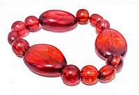 Photo of vintage Lucite stretch bracelet showing translucent red oval and round beads on elastic string.